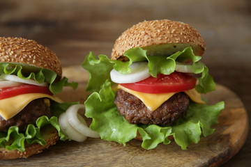 Close-up. Two hamburger with beef cutlet, with cheese, pickles, tomatoes, onions, lettuce on a wooden rustic background.