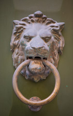 Fototapeta na wymiar Old rusty iron lion head door knocker on a wooden door. Mdina, Malta