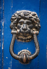 Old rusty iron lion head door knocker on a wooden azure door. Mdina, Malta