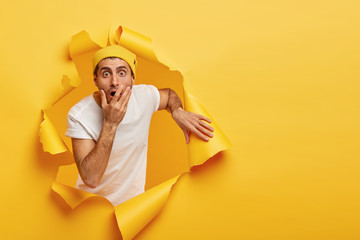 Image of frightened puzzled guy covers mouth, stares with scared expression, cannot believe his...