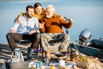 Senior grandfather having warm conversation with his adult son and daughter during the picnic near...