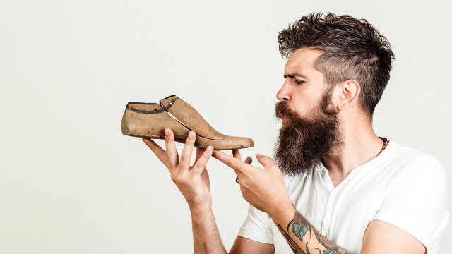 Young designer holding a wooden last shoe on white background. Creative idea of new shoes model. Serious young cobbler sets up business. Modelling design of a shoes.