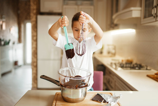 Litte boy stirs melted chocolate in a bowl