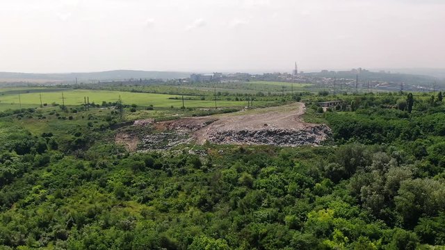 Rotating aerial of a flattened out rubbish dump being pushed ever further into the woods below