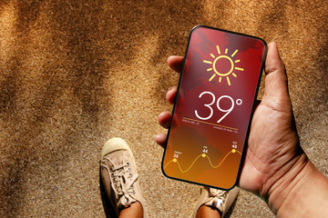 Ecology and Technology Concept. High Temperature Weather show on Mobile Screen on Hot Sunny Day....