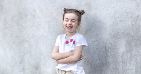 Cheerful little girls on gray textured background. Outdoor portrait little girl. Gray textured wall background.