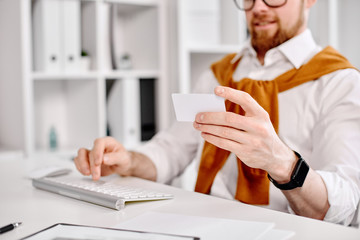 Mid age businessman working with plastic card at the computer in the office