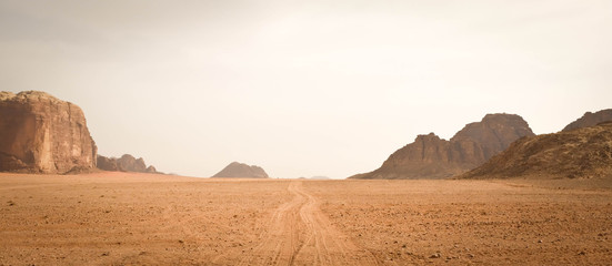 Fototapeta na wymiar Sand pathway through Wadi Rum desert, Jordan. Mountain range in the background.