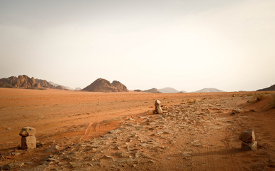 dusty path in the middle of Wadi Rum Desert, Jordan. Three stone figures placed around for orientation purpose.