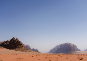 Fototapeta na wymiar View on sandy valley in Wadi Rum desert, Jordan. Mountain range made from sandstone in the background.