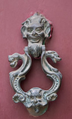 An old style decorative bronze door handle on a wooden door, the distinctive feature and symbol of...