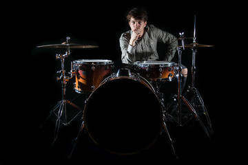 Professional drummer playing on drum set on stage on the black background