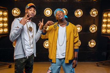 Two black rappers in caps, artists poses on stage