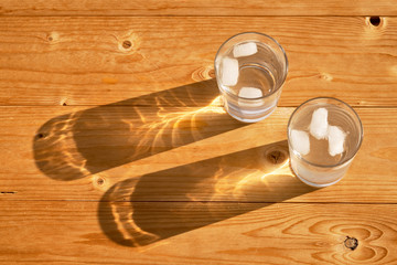 two glasses with ice water on a wooden table, refraction of light in water
