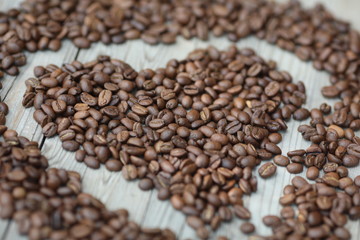 Coffe beans in hands and on the wooden  table, roasted arabica