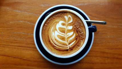 Hot cappuccino coffee in the cup on wood table. Cappuccino mixed with espresso coffee, milk is a fine foam and milk pressurized steam. Sometime garnished with cinnamon powder or cocoa powder on coffee