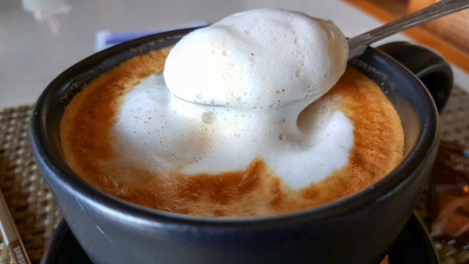 Hot cappuccino coffee in the cup on wood table. Cappuccino mixed with espresso coffee, milk is a fine foam and milk pressurized steam. Sometime garnished with cinnamon powder or cocoa powder on coffee