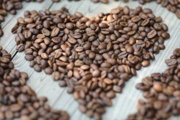 Coffe beans in hands and on the wooden  table, roasted arabica
