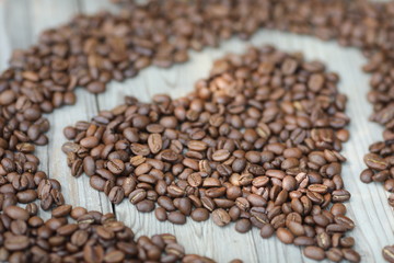 Coffe beans in hands and on the wooden  table, roasted arabica