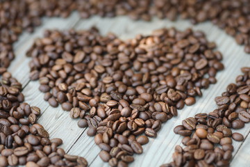 Coffe beans in hands and on the wooden  table, roasted arabica