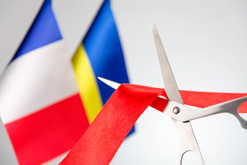 Ribbon cutting ceremony. Scissors cut red ribbon. .Ukraine and France flag bluered on the background. start of a partnership concept
