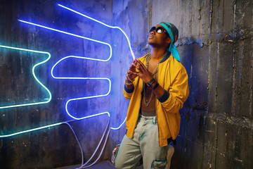 Black rapper in underpass neon light on background