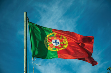 Naklejka na ściany i meble Portuguese flag fluttering in the blue sky