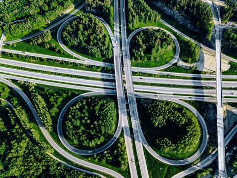 Aerial view of highway and overpass with green woods in Finland.