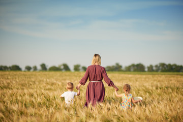 Family values. Happy mother and her children spending time together in sunny field. Mom hugging and...