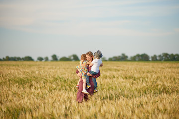 Naklejka premium Family values. Happy mother and her children spending time together in sunny field. Mom hugging and loving her little kids. Care concept