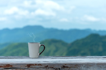 Cup coffee and tea with steam on wood table outdoor over mountains landscape with sunlight. Beauty nature background. Lifestyle Concept