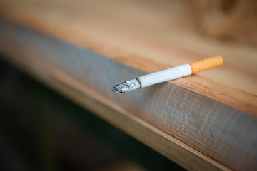 Closeup of burned cigarette on the wooden table
