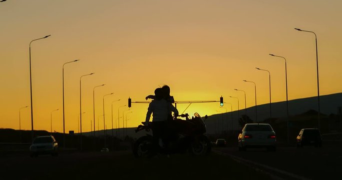 couple in love standing next to a motorcycle during sunset