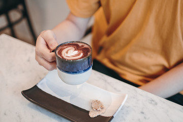 Asian man on yellow T-shirt, Selected focus,hand holding the glass hot coffee in the cafe or restaurant.