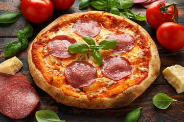 Homemade Pepperoni, Salami Pizza with basil, tomatoes, cheese on wooden table. ready to eat