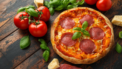 Homemade Pepperoni, Salami Pizza with basil, tomatoes, cheese on wooden table. ready to eat