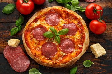 Homemade Pepperoni, Salami Pizza with basil, tomatoes, cheese on wooden table. ready to eat