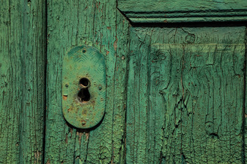 Close-up of wrought iron keyhole in an old wooden worn door