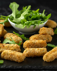 Fried mozzarella cheese sticks in breadcrumbs with wild rocket leaves