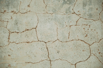 Wall covered by rough plaster with some cracks and chipped