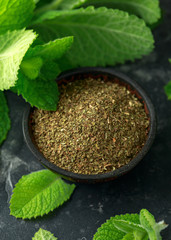 Fresh and dried mint in bowl. on black rustic table