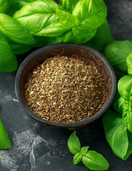 Fresh and dried basil in bowl. on black rustic table