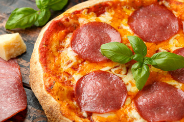 Hot Pepperoni, Salami Pizza with basil, tomatoes, cheese on wooden table. ready to eat