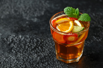 Refreshing Pimms Cocktail with Fruit and vegetables on rustic black table