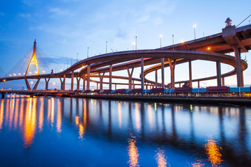 Naklejka na ściany i meble Low angle view of highway interchange and suspension bridges at dusk.