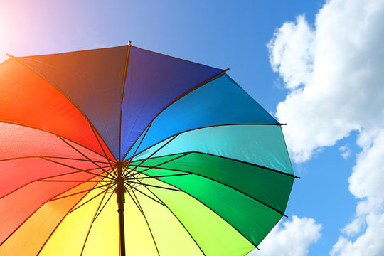 multicolor rainbow umbrella on blue sky background. rainbow umbrella against cloudy blue sky. weather concept. summer season. rainbow umbrella against cloudy blue sky. copy space. soft focus
