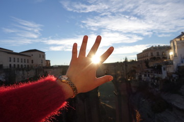 Close-up of the hand caught in the sun and the sky