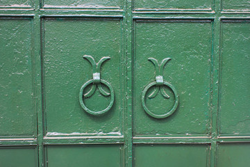 Green vintage door with ring handles at old mansion entrance 