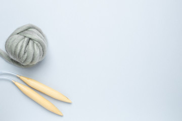 Circular knitting needles and thick grey yarn on blue background