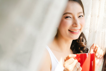 beautiful asian woman enjoy morning time with hot drink in bedroom with window light